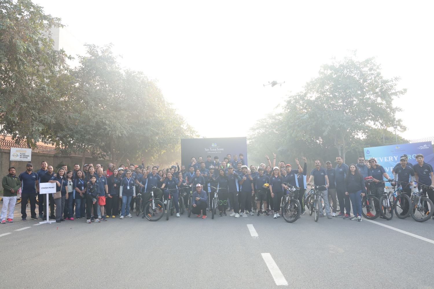 The full cyclothon crowd at the finish point, cheering, with a drone overhead